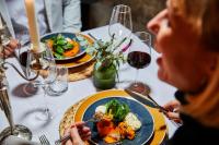 Dos personas sentadas en una mesa con un plato de comida. en Weinforum Franken Hotel & Restaurant, en Eibelstadt