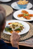 a person sitting at a table with plates of food at Ferns Hideaway Resort in Byfield