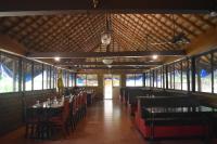 una sala da pranzo con tavoli, sedie e finestre di Ibex River Resort, Pollachi a Coimbatore