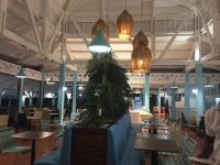 ein Restaurant mit Tischen und Stühlen und Pendelleuchten in der Unterkunft STUDIO CARAMBOLE VUE MER - Piscines - Plages - Village vacances Sainte Anne Guadeloupe in Sainte-Anne
