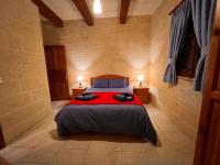 a bedroom with a large bed with a red blanket at Ta’ Peppi Farmhouse in Qala