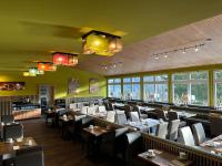 uma sala de jantar com mesas, cadeiras e janelas em Maiers Hotel em Bayerisch Eisenstein