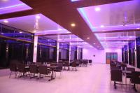 een feestzaal met tafels en stoelen en paarse verlichting bij Ashoka Lawns and Resort in Alibaug