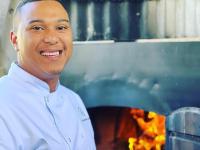 a man is standing in front of a grill at Klaarstroom Hotel in Klaarstroom
