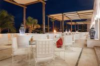 um bar com cadeiras e mesas brancas e palmeiras em Marquis Los Cabos, an All - Inclusive, Adults - Only & No Timeshare Resort em San José del Cabo