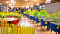 Un restaurante con sillas y mesas de colores brillantes y un escritorio. en Hotel Indigo Alishan by IHG, en Fanlu
