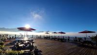 a deck with tables and umbrellas on the water at Naluwan Villa in Ren&#39;ai