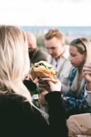 a woman holding a sandwich in front of a group of people at Surflogiet Gotland in Tofta