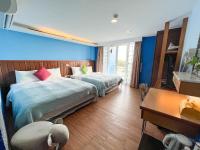 a bedroom with two beds with blue walls and a desk at Tz Shin Resort Hostel in Kenting