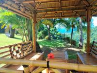 a wooden porch with two benches and palm trees at Gîte 4 étoiles, la Vieille Sucrerie St Claude Guadeloupe, Jacuzzi Spa privatif, vue exceptionnelle sur la mer des Caraïbes in Basse-Terre