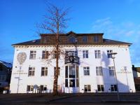 Un edificio blanco con un árbol delante. en Hotel Leifur Eiriksson, en Reikiavik