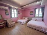 a pink bedroom with two beds and a chair at 伊莎愛莉溜滑梯親子民宿 in Wujie