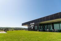 Un edificio negro con mesas y sillas en el césped. en Beresford Estate, en McLaren Flat