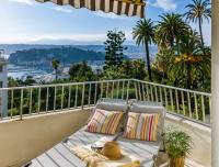 una silla en el balcón con vistas a la ciudad en Ferienwohnung Les Oliviers über den Dächern von Nizza ruhig sonnig Meerblick Pool Tiefgarage Parkplatz, en Niza