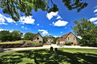 a green yard with two houses and a blue sky at Manoir de Malagorse in Cuzance