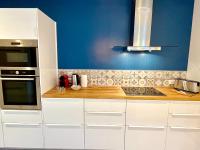 a kitchen with white cabinets and a blue wall at Le Jardin Des Sacres - HyperCentre Cathédrale in Reims