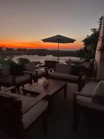 a group of tables and chairs with a sunset in the background at Suítes Luxo Marambaia- Epic House in Rio de Janeiro