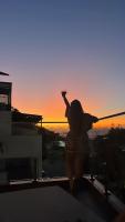 a woman standing on top of a building at sunset at Suítes Luxo Marambaia- Epic House in Rio de Janeiro