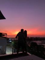 a man and a woman standing on a balcony at sunset at Suítes Luxo Marambaia- Epic House in Rio de Janeiro