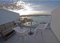 a balcony with a glass table and two white chairs at Suítes Luxo Marambaia- Epic House in Rio de Janeiro