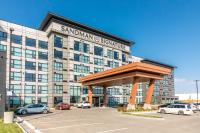 Un gran edificio con coches aparcados en un estacionamiento. en Sandman Signature Saskatoon South Hotel, en Saskatoon