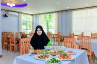 Eine Frau, die an einem Tisch mit Teller Essen sitzt. in der Unterkunft Saline Hot Spring Resort นำ้พุร้อนเค็ม รีสอร์ท in Ban Nam Ron (1)