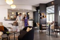 a man and a woman walking through a lobby at Hôtel Plaza Étoile in Paris