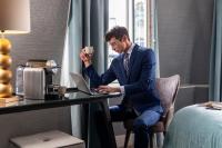 a man in a suit sitting at a desk with a laptop at Hôtel Plaza Étoile in Paris