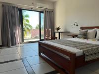 Un dormitorio con una cama grande y una ventana grande. en Hôtel Grand Bay, en Nosy Be