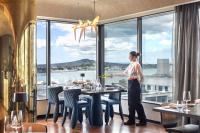 a woman standing at a table in a restaurant with a view at SO/ Auckland in Auckland