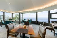 a dining room with tables and chairs and the ocean at STANFORD Hotel & Resort Jeju in Jeju