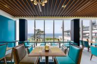 a restaurant with blue chairs and a table with a view of the ocean at STANFORD Hotel & Resort Jeju in Jeju