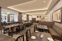 Un restaurante con mesas y sillas en una sala. en Sangam Hotel, Thanjavur, en Thanjāvūr