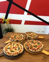 four pizzas sitting on a wooden table in front of a flag at SoHo NewYork in Toucheng
