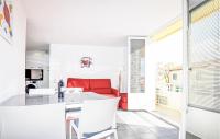 a kitchen and living room with a red couch at Amazing Apartment In Saint Cyprien Plage With Wifi in Saint-Cyprien-Plage