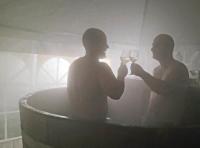 two men in a bath tub holding glasses of wine at Végvári Vendégház in Magyarbóly