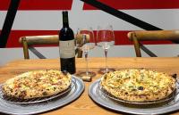 two pizzas sitting on a wooden table with wine glasses at SoHo NewYork in Toucheng