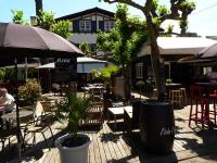 Un patio con mesas y sillas y un árbol. en Etche Ona, en Pyla-sur-Mer