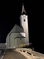 a white church with a clock tower at night at groassehof Haus Gstrein in Imsterberg