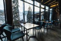 a restaurant with tables and chairs and large windows at BLUE mountain in Bukovel