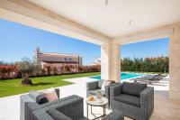 eine Terrasse mit 2 Stühlen, einem Tisch und einem Pool in der Unterkunft Villa Grace by ILC (Istria Luxury Collection) in Brtonigla