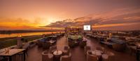 a rooftop deck with chairs and tables and a sunset at Eastin Hotel Vientiane in Vientiane