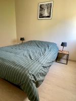 a bed with a blue comforter in a bedroom at L&#39;écureuil de la Baie - maison en Baie de Somme in Mons-Boubert