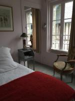 a bedroom with a bed and a chair and windows at Logis Saint-Léonard in Honfleur