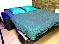 an unmade bed with blue pillows on top of it at La marbrière, Parking gratuit, proche centre ville in Sens