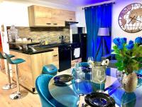 a kitchen with a glass table and blue chairs at La marbrière, Parking gratuit, proche centre ville in Sens