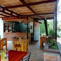 un patio con mesas y sillas de madera y una cocina en Sendero de las aves, en Mindo