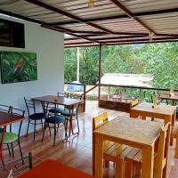 Un restaurante con mesas y sillas y un gran ventanal. en Sendero de las aves, en Mindo