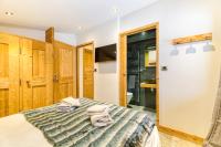 a bedroom with a bed and a tv and a closet at Alpes Sweet Home - Chalet La Biche in L&#39;Alpe-d&#39;Huez