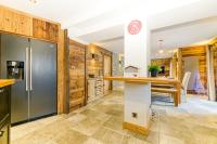 a kitchen with wooden walls and a table with a refrigerator at Alpes Sweet Home - Chalet La Biche in L&#39;Alpe-d&#39;Huez